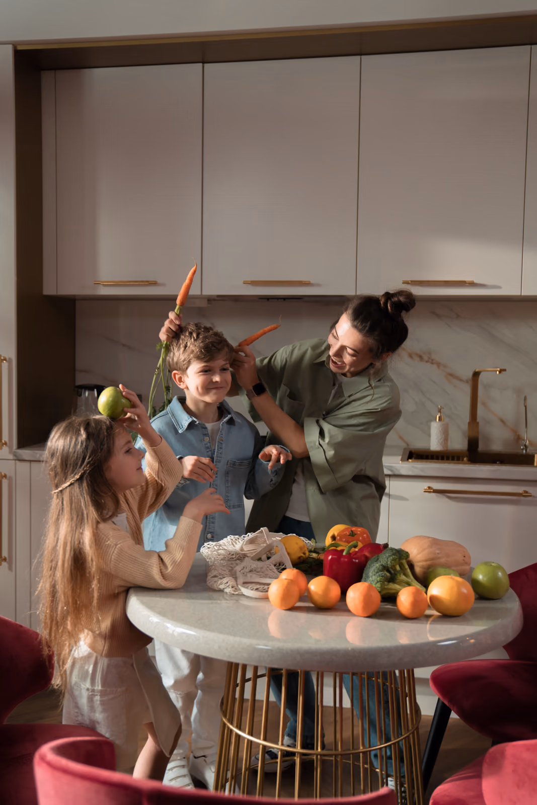 A parent and two children laughing together over a table of fresh fruit and vegetables